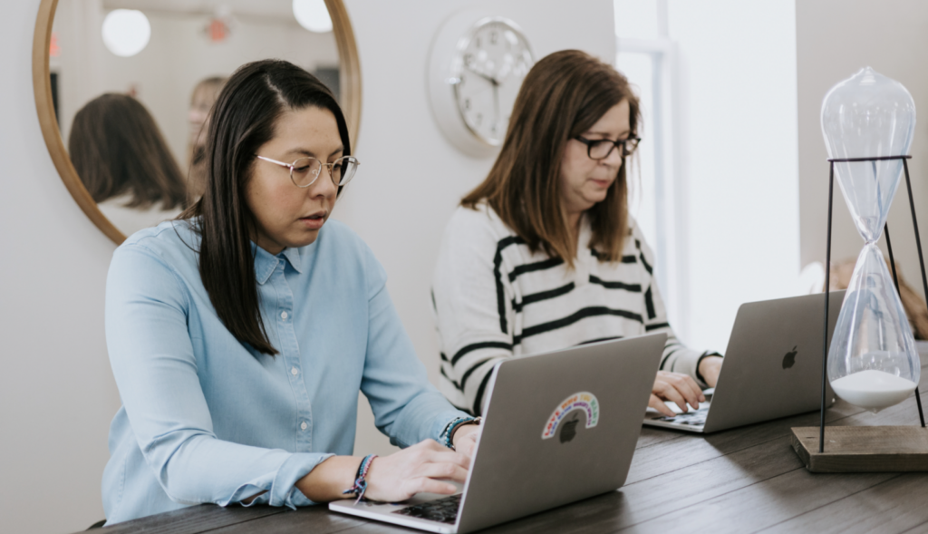Benefits of Diversity in the Workplace: Great for Culture, Equity, Innovation, and Profitability 5 Two women at a table in an office setting.