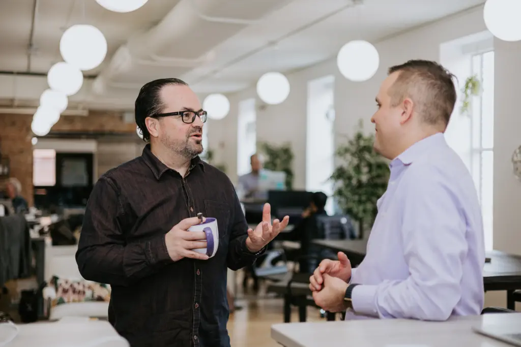 What to Expect from a Mentorship Program 4 Two men engaging in a mentoring conversation within an office setting.