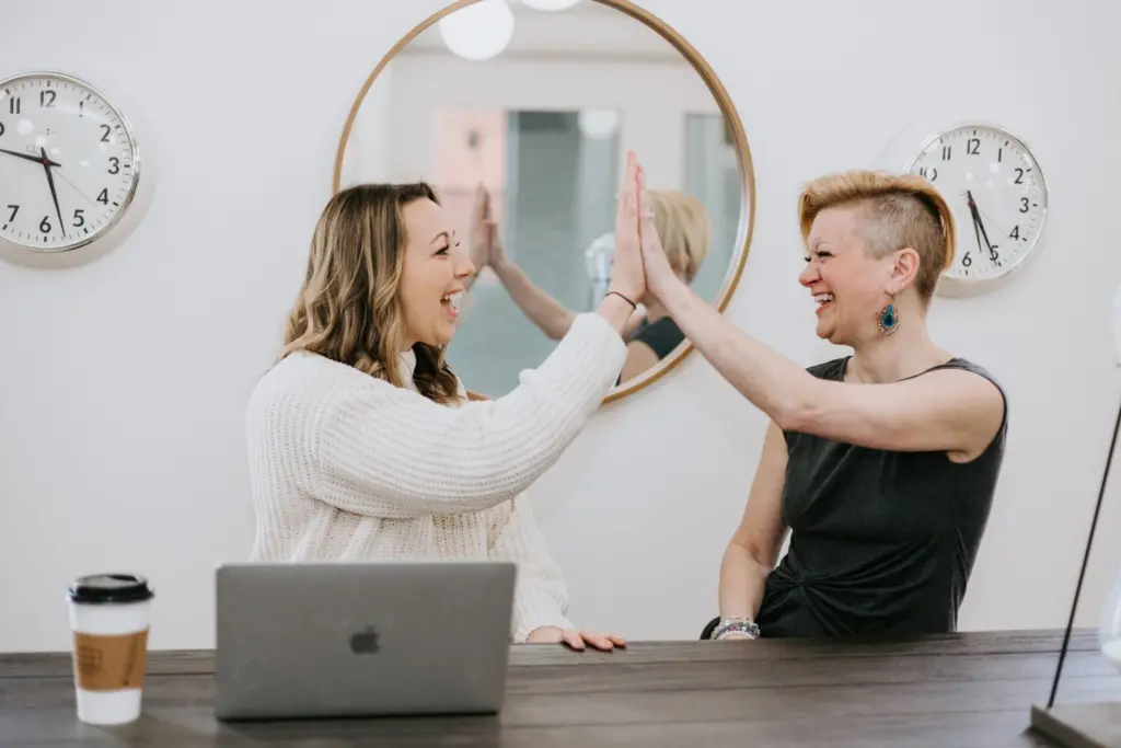 Jumpstart Guide to Building a Women's Employee Resource Group 7 Two women in a Women's ERG celebrating success with a high five.