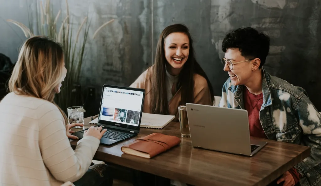 Mentoring Activities: Our 10 Favorite Mentoring Activities to Boost Engagement 10 Three work colleagues networking and working on their laptops in a casual office setting.