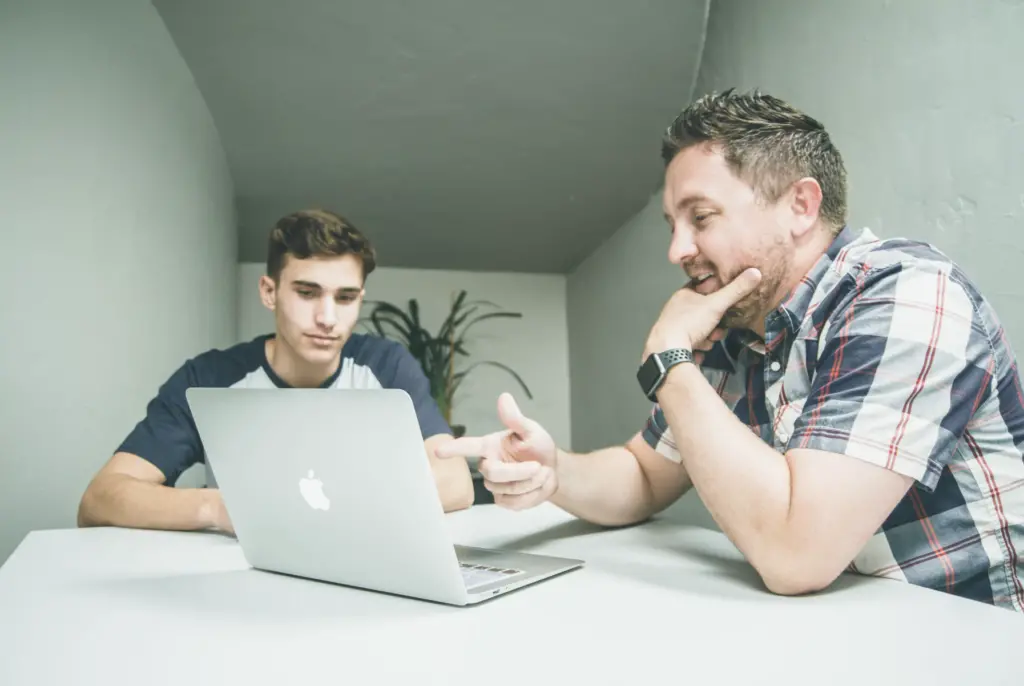 What Is Succession Planning? Key Definition and Strategies 5 Father and son sit at a table discussing succession for their family owned business.